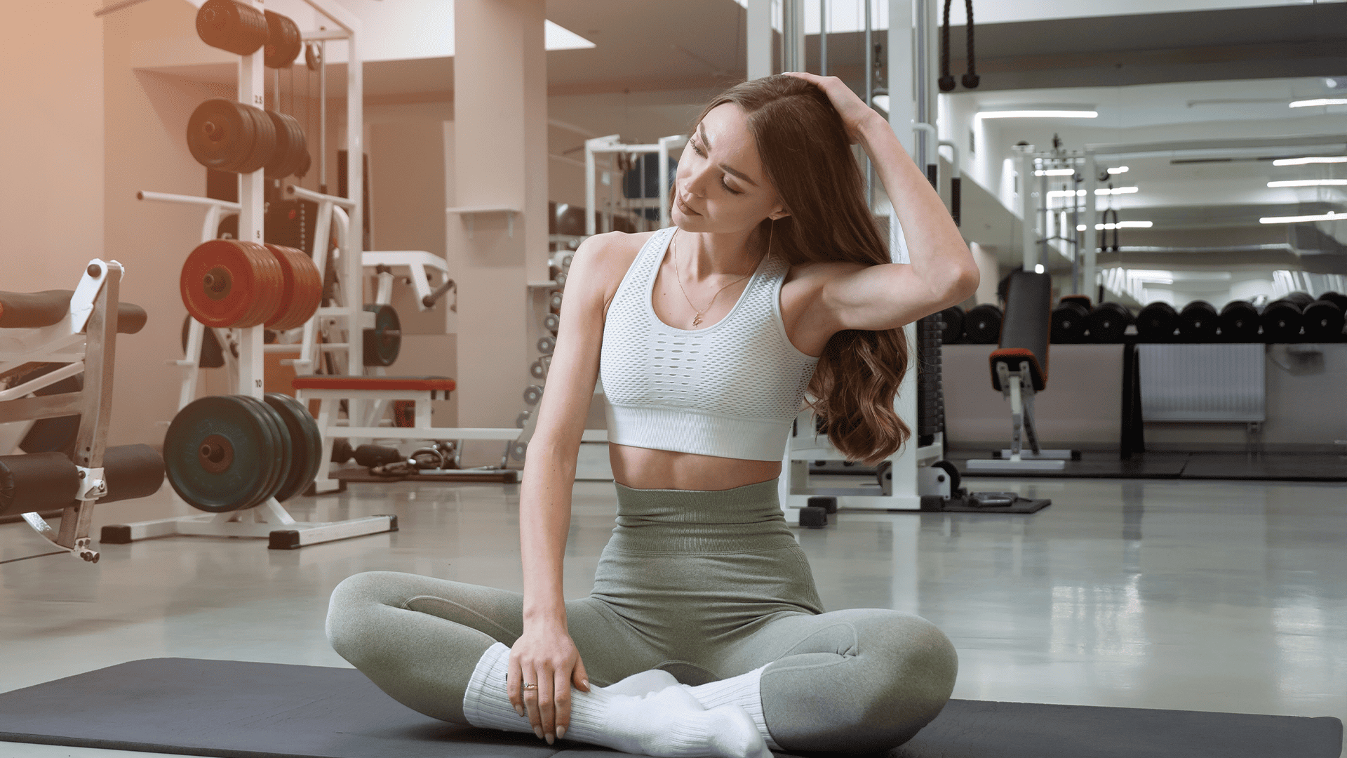 A young woman at the gym stretching in workout clothes 
