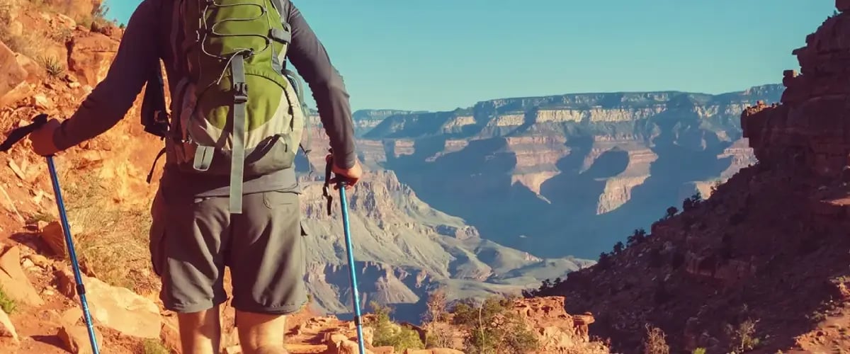 Hiker with trekking poles explores Arizona canyon, promoting active spine and joint health.