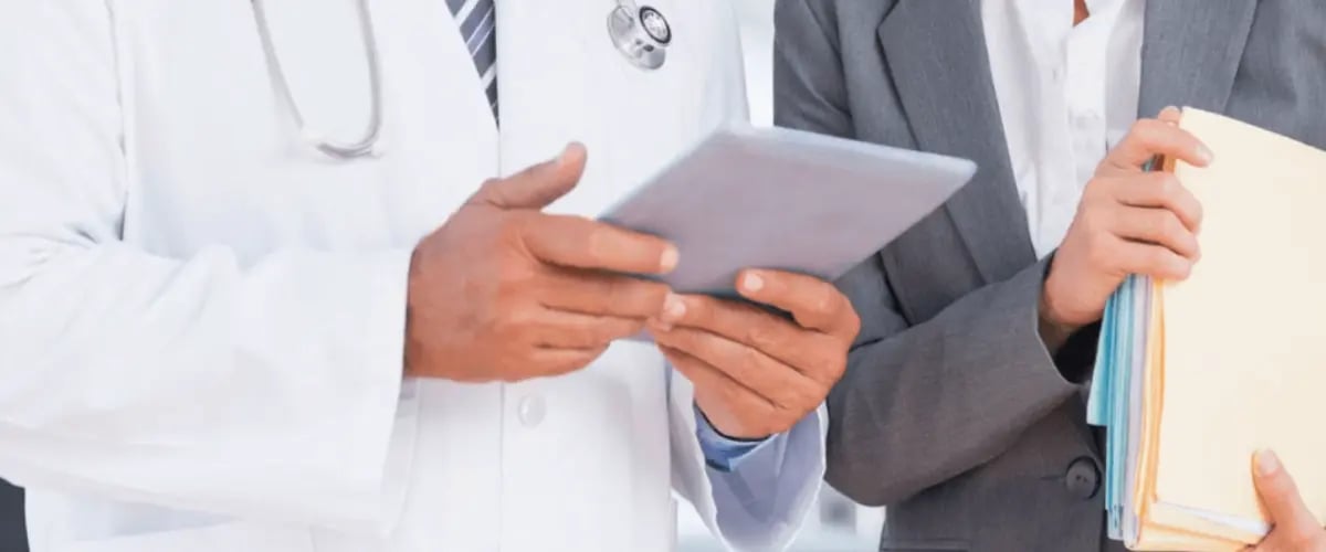 Doctor reviews patient data on a tablet with a colleague, highlighting collaborative care at Desert Spine and Sports, Arizona.