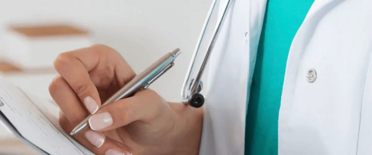 Doctor in a white coat taking notes, symbolizing professional spine and sports care at Desert Spine and Sports Physicians, Arizona.