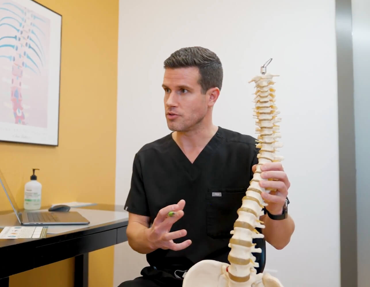 Physiatrist explaining spinal health with a model, promoting wellness through personalized care and spinal alignment expertise.