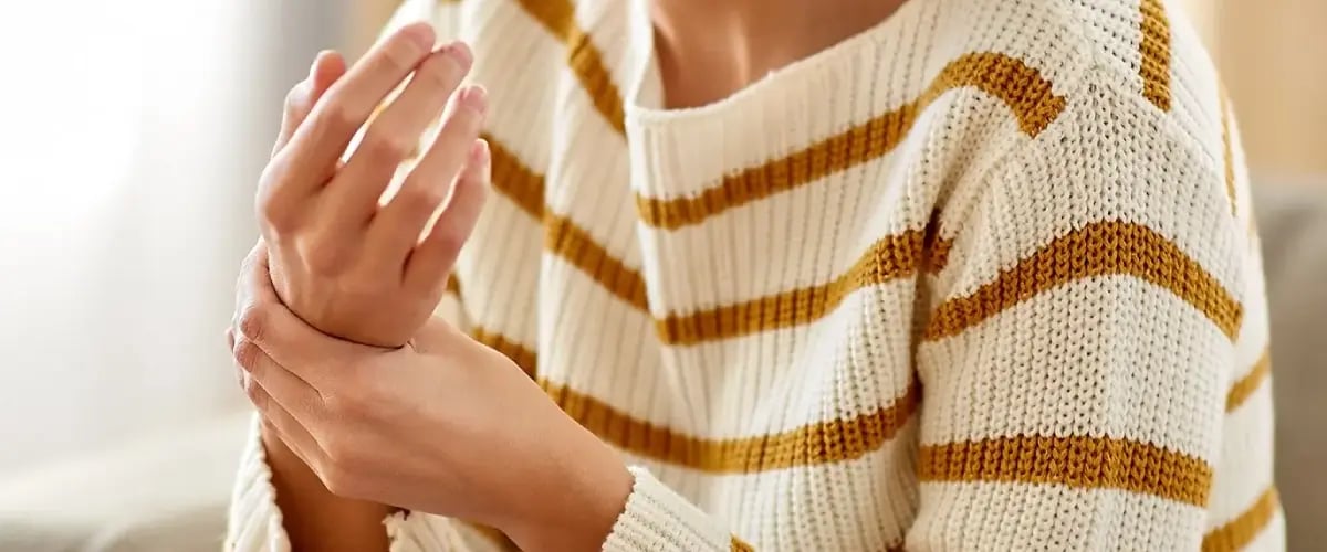 Patient holding wrist in pain, seeking relief at Desert Spine and Sports Physicians, Arizona. Specialized care for joint health.