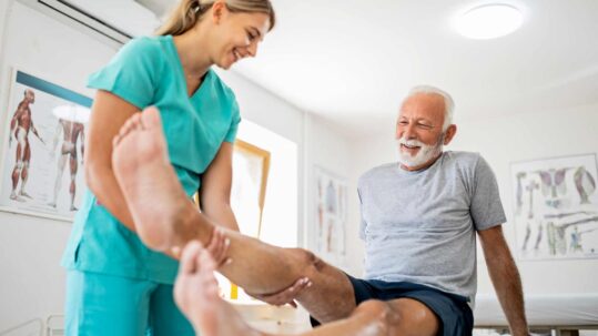 senior men with knee pain receiving physical therapy from a physician