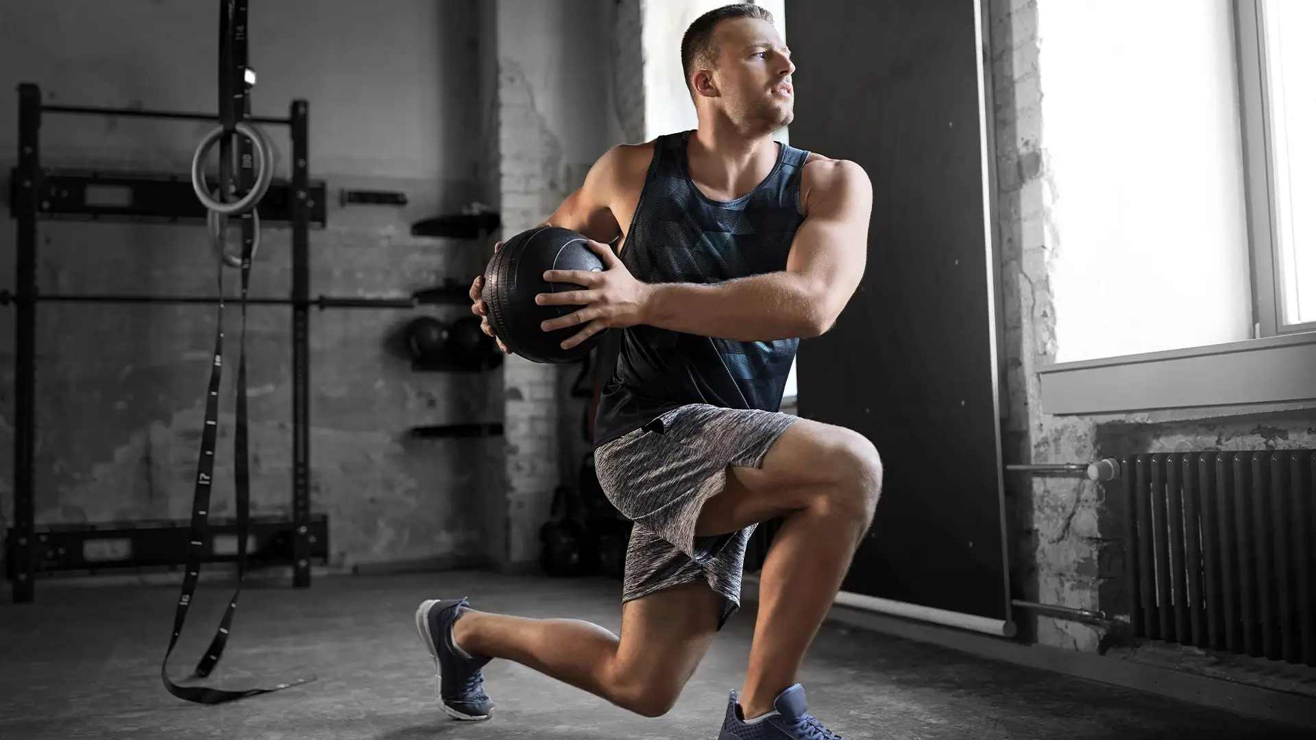 Man performing a lunge with medicine ball in gym, enhancing recovery from herniated disc.