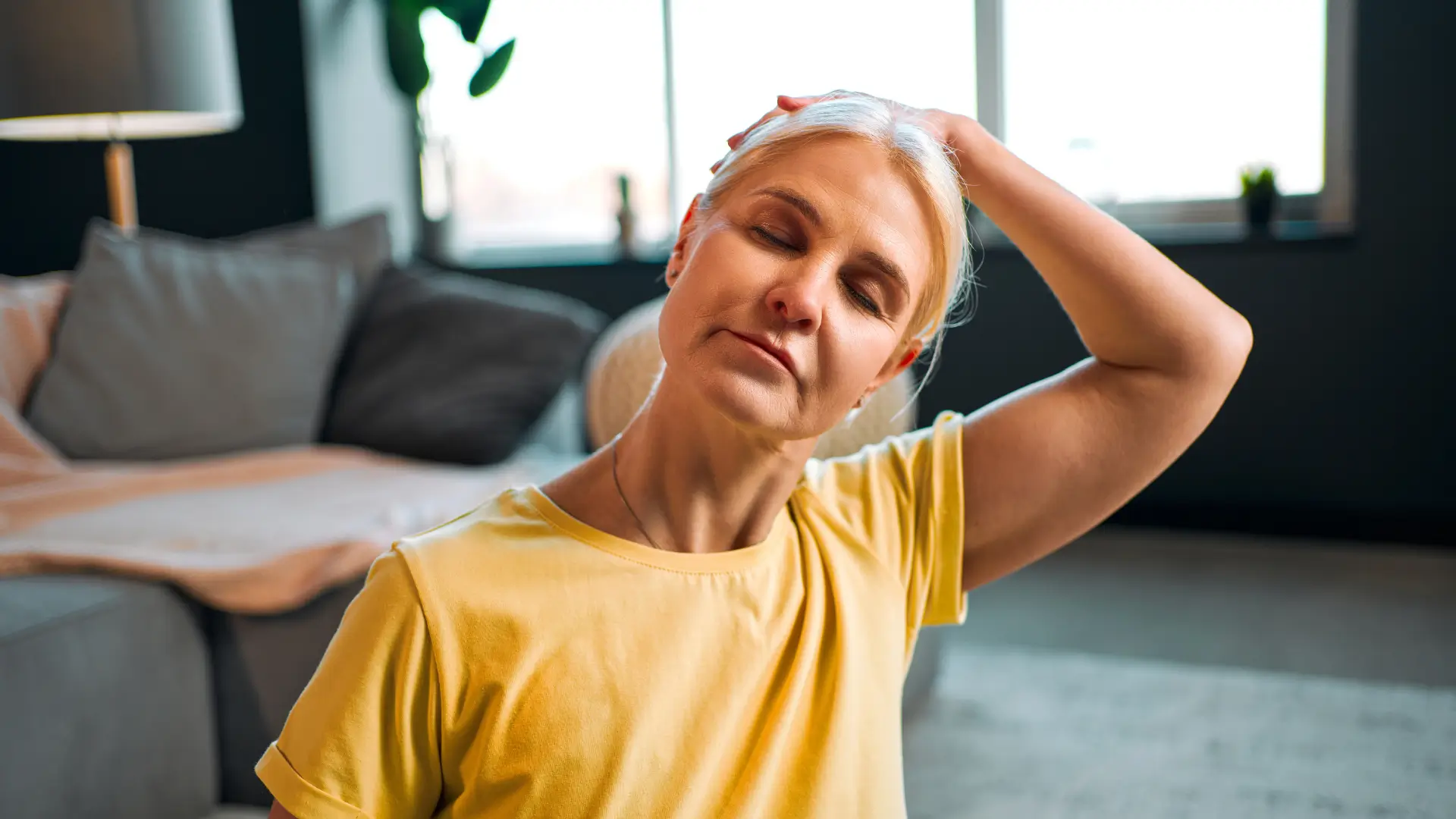 Woman practicing neck stretches at home for improved flexibility and tension relief.